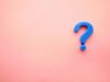 Signo de interrogación azul de plástico sobre un fondo rosa pastel, simbolizando la duda de los estudiantes sobre si su nivel B2 de inglés sigue siendo suficiente o necesitan el C1