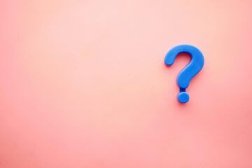 Signo de interrogación azul de plástico sobre un fondo rosa pastel, simbolizando la duda de los estudiantes sobre si su nivel B2 de inglés sigue siendo suficiente o necesitan el C1