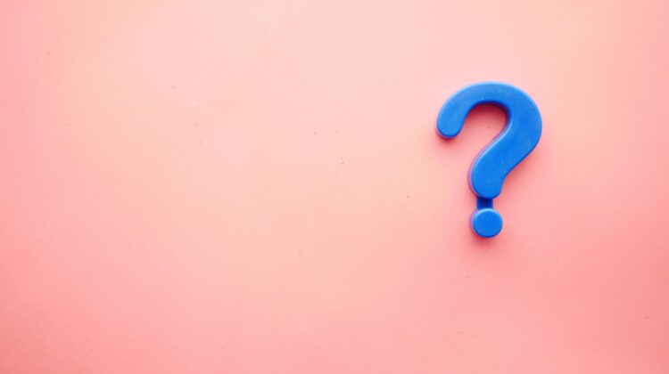 Signo de interrogación azul de plástico sobre un fondo rosa pastel, simbolizando la duda de los estudiantes sobre si su nivel B2 de inglés sigue siendo suficiente o necesitan el C1
