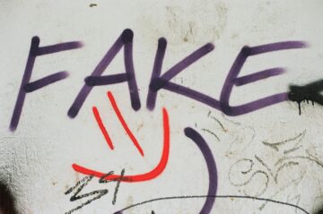 Graffiti en una pared blanca con la palabra FAKE (falso) pintada en letras moradas, simbolizando la trampa visual y el engaño de los falsos amigos en el vocabulario en inglés