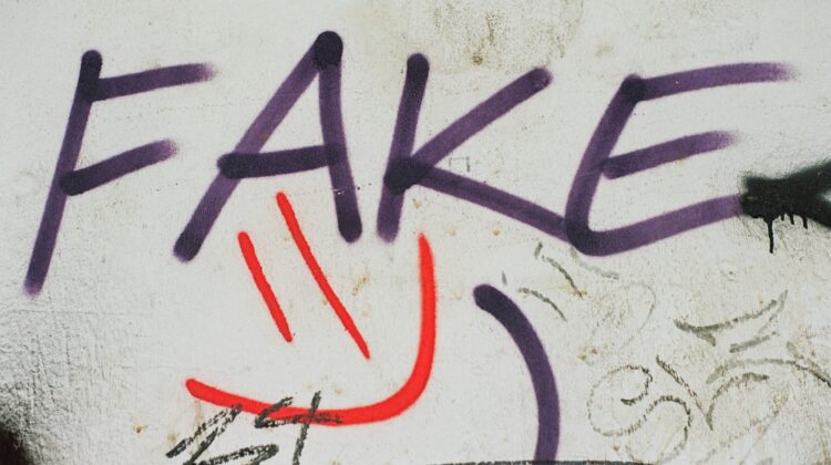 Graffiti en una pared blanca con la palabra FAKE (falso) pintada en letras moradas, simbolizando la trampa visual y el engaño de los falsos amigos en el vocabulario en inglés