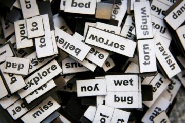 Primer plano de muchas piezas magnéticas con palabras en inglés desordenadas, representando la construcción de frases y la dificultad de traducir expresiones idiomáticas literalmente