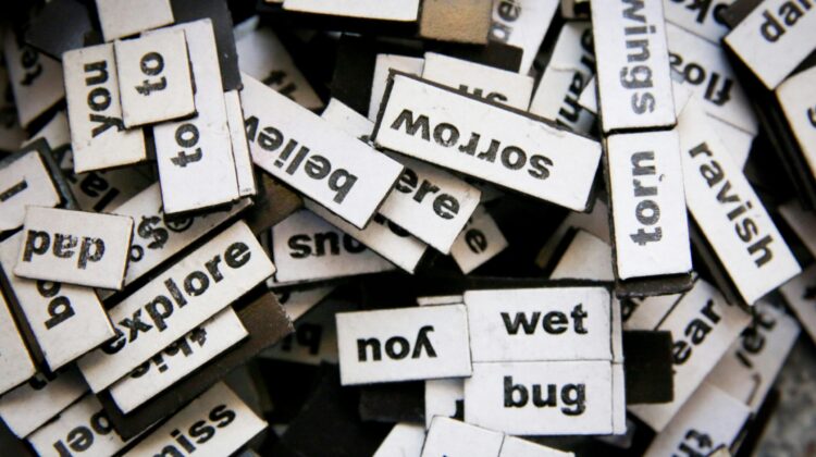 Primer plano de muchas piezas magnéticas con palabras en inglés desordenadas, representando la construcción de frases y la dificultad de traducir expresiones idiomáticas literalmente