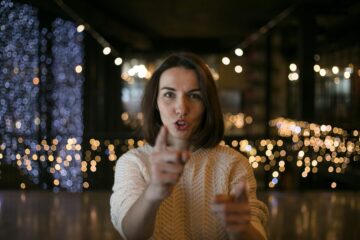 Mujer joven señalando directamente a la cámara con expresión de sorpresa, representando la tensión y el bloqueo mental al enfrentarse a las preguntas del examinador en la prueba de Speaking