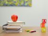 Manzana roja sobre una pila de libros y bloques del abecedario sobre un escritorio de madera, representando el baremo de méritos en las oposiciones de educación