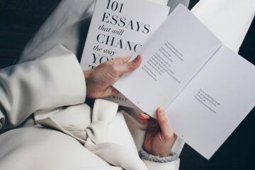 Primer plano de una persona leyendo un libro de ensayos, representando la redacción y estructura de textos académicos en inglés