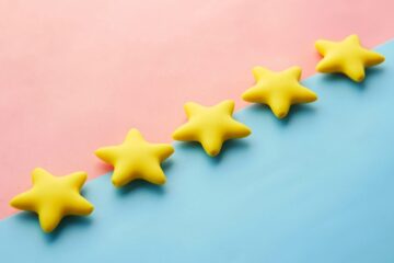 Cinco estrellas amarillas alineadas sobre un fondo rosa y azul, representando la valoración y el veredicto final de una reseña (review) en inglés