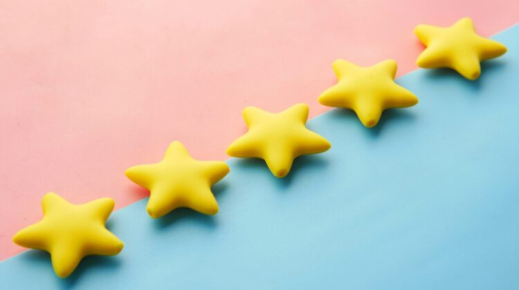 Cinco estrellas amarillas alineadas sobre un fondo rosa y azul, representando la valoración y el veredicto final de una reseña (review) en inglés