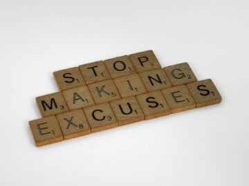 Fichas de Scrabble de madera sobre fondo blanco que forman la frase en inglés "Stop making excuses" (Deja de poner excusas).