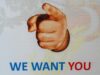 Cartel con una mano que señala al espectador y el texto «WE WANT YOU» en letras azules y rojas sobre fondo blanco